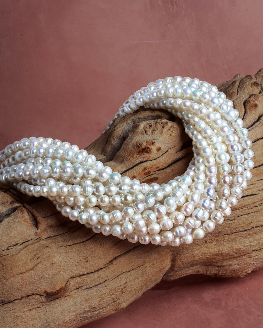 White freshwater pearl strands draped over driftwood